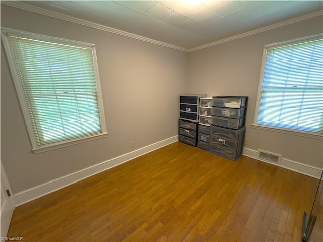 empty room featuring visible vents, baseboards, plenty of natural light, and wood finished floors