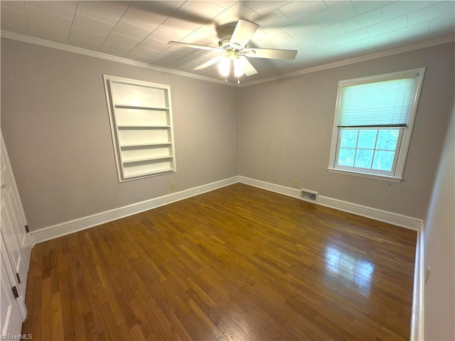 unfurnished room featuring dark wood-style floors, crown molding, visible vents, and built in features