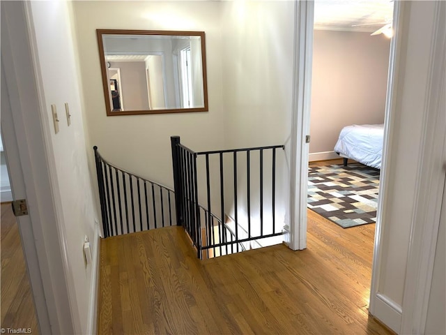 hallway featuring baseboards, an upstairs landing, and wood finished floors
