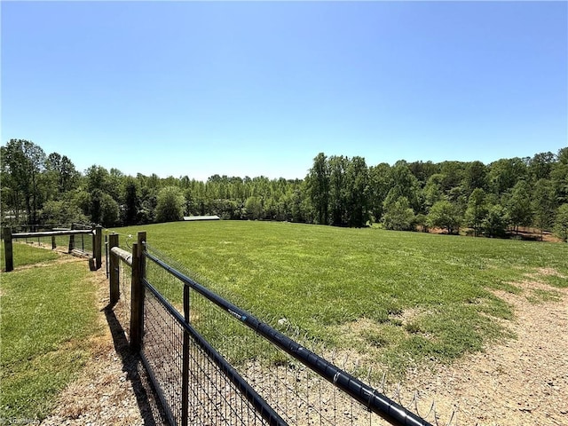 view of yard with a wooded view, fence, and a rural view
