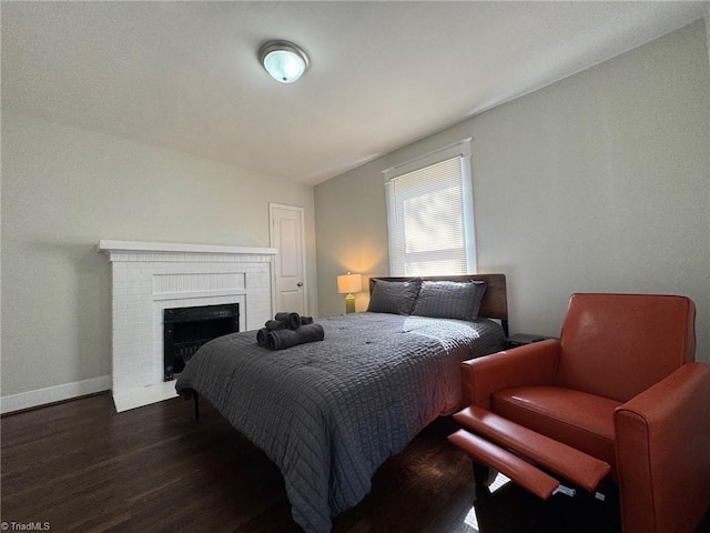 bedroom featuring dark wood-type flooring, a fireplace, and lofted ceiling