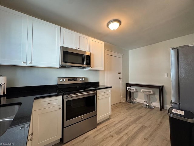 kitchen featuring white cabinets, light wood-type flooring, and stainless steel appliances