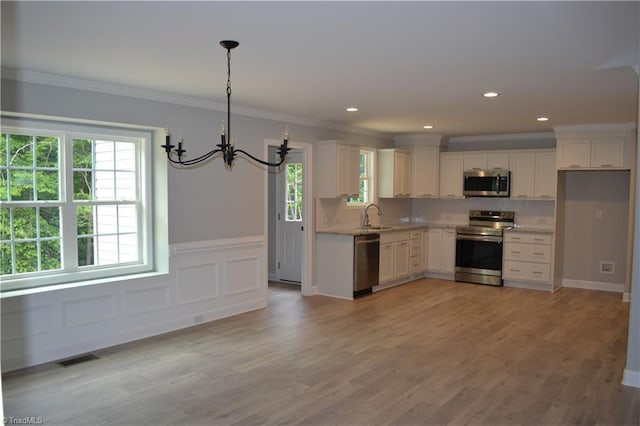 kitchen with white cabinets, decorative light fixtures, stainless steel appliances, and a healthy amount of sunlight