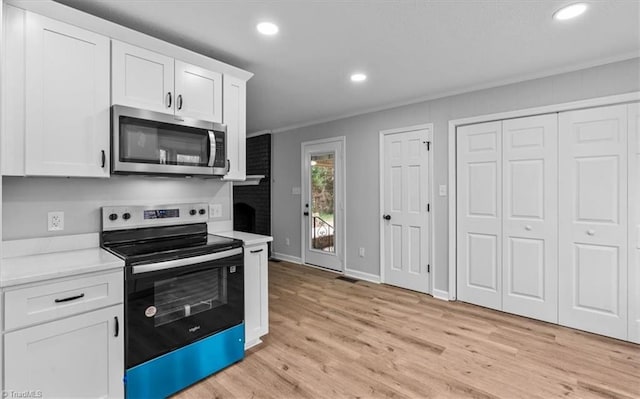 kitchen with light countertops, appliances with stainless steel finishes, light wood-style flooring, and white cabinets