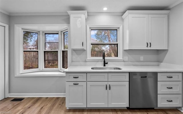 kitchen featuring dishwasher, light countertops, a sink, and baseboards