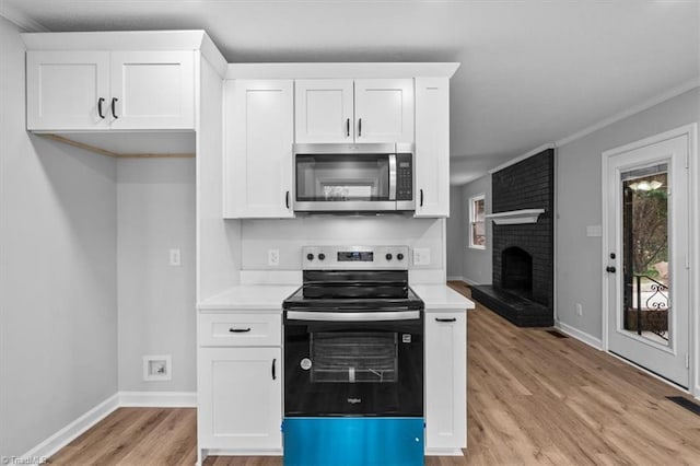 kitchen with range with electric cooktop, white cabinets, stainless steel microwave, and light wood finished floors