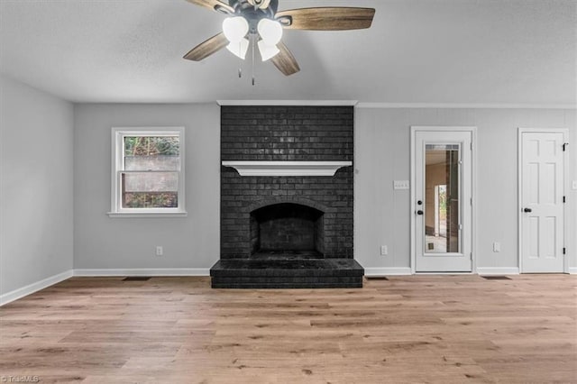 unfurnished living room with a fireplace, a textured ceiling, baseboards, and wood finished floors