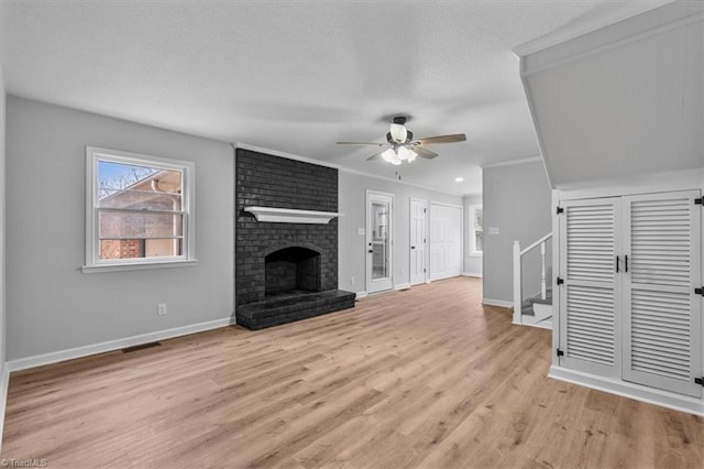 unfurnished living room with light wood-style floors, a fireplace, a textured ceiling, and a ceiling fan