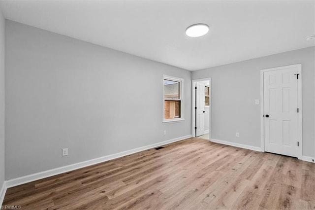 unfurnished room featuring wood finished floors, visible vents, and baseboards