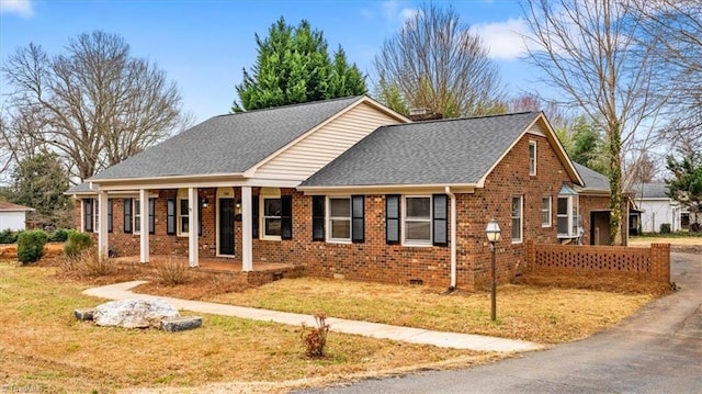 ranch-style home with brick siding, a front yard, a porch, and a shingled roof