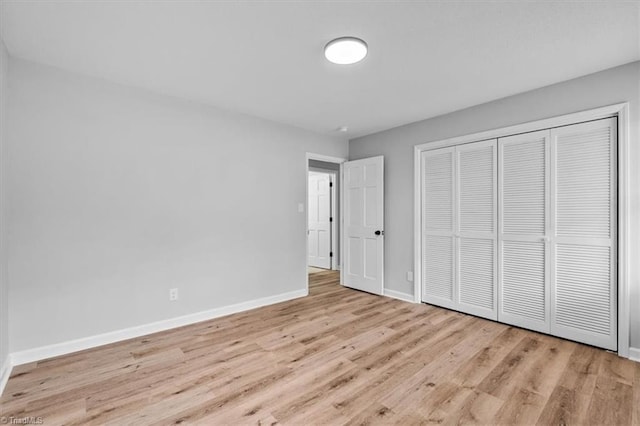 unfurnished bedroom with a closet, baseboards, and wood finished floors