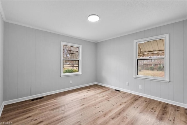 unfurnished room featuring visible vents, crown molding, baseboards, and wood finished floors