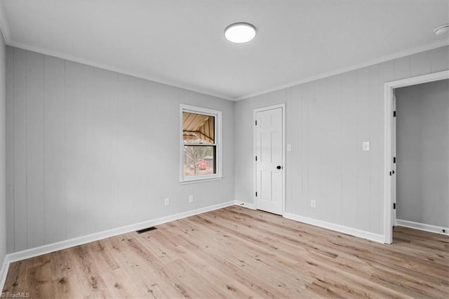 spare room with crown molding, baseboards, and wood finished floors