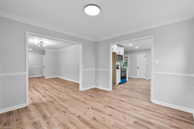 unfurnished room featuring light wood-style floors, ornamental molding, and wainscoting