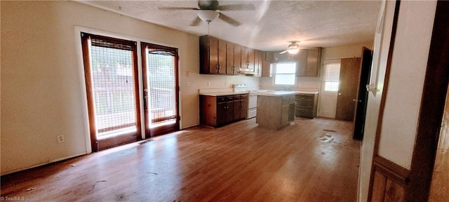 305 Corliss St, Greensboro, NC 27406 - kitchen featuring white range with electric stovetop, a ceiling fan, light wood-style flooring, under cabinet range hood, and a center island
