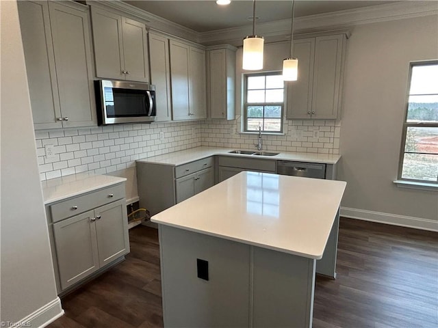 kitchen with appliances with stainless steel finishes, a center island, gray cabinetry, and sink