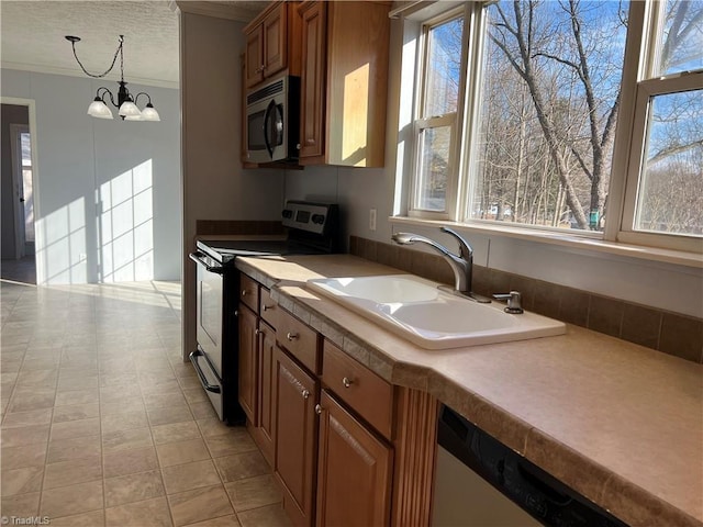 kitchen with sink, appliances with stainless steel finishes, an inviting chandelier, hanging light fixtures, and ornamental molding