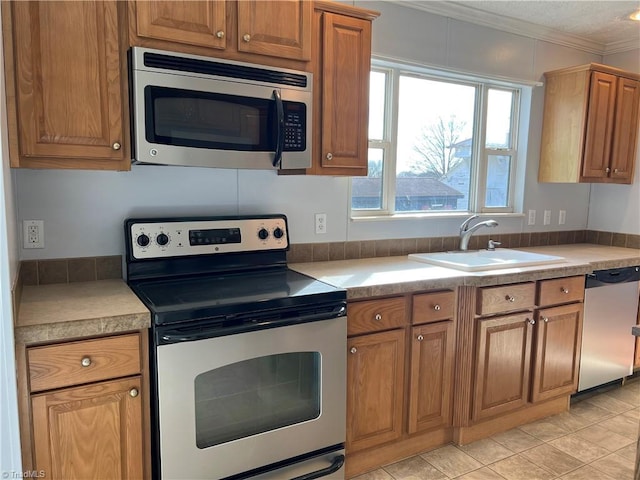 kitchen with sink, light tile patterned floors, ornamental molding, and stainless steel appliances