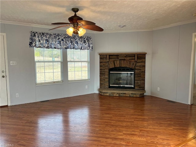 unfurnished living room featuring wood-type flooring, ornamental molding, a textured ceiling, and a fireplace