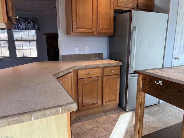 kitchen featuring light tile patterned floors, ornamental molding, and stainless steel refrigerator