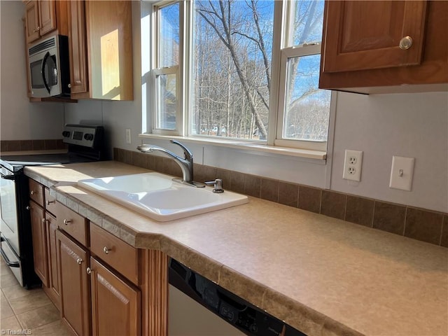 kitchen with sink, light tile patterned floors, stainless steel appliances, and a healthy amount of sunlight