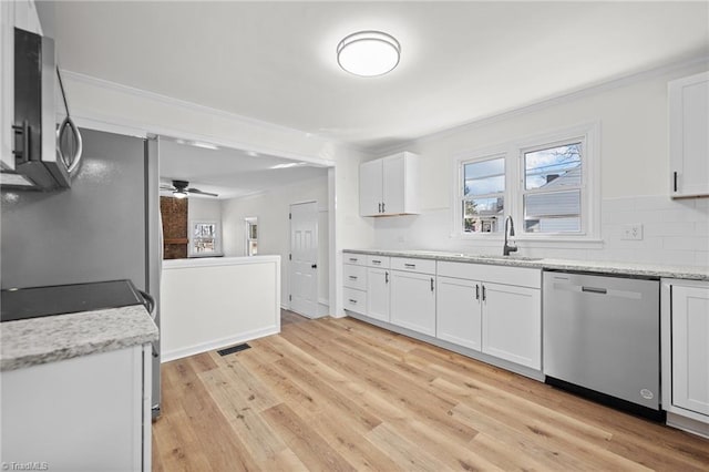 kitchen featuring light wood-type flooring, a sink, backsplash, stainless steel appliances, and white cabinets