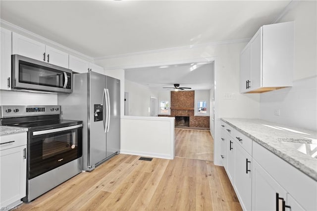 kitchen featuring a ceiling fan, white cabinetry, stainless steel appliances, light wood-style floors, and decorative backsplash