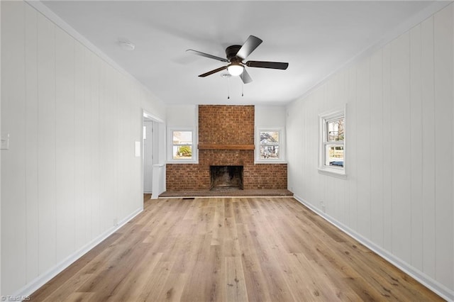 unfurnished living room with a ceiling fan, light wood-style floors, baseboards, and a fireplace