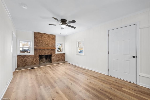 unfurnished living room with light wood-style flooring, a fireplace, crown molding, and a ceiling fan