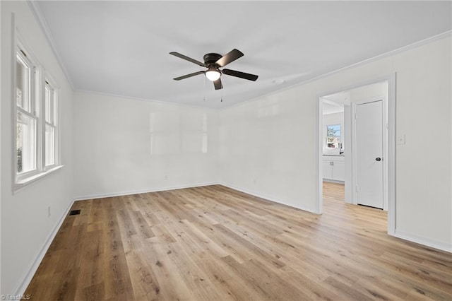 empty room with light wood finished floors, visible vents, crown molding, and ceiling fan