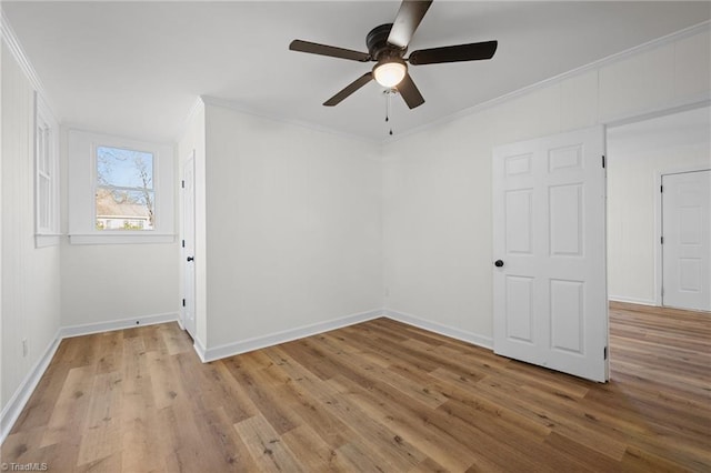 empty room featuring a ceiling fan, crown molding, wood finished floors, and baseboards