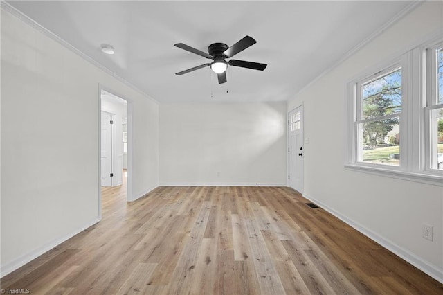 spare room with baseboards, visible vents, light wood finished floors, ceiling fan, and crown molding