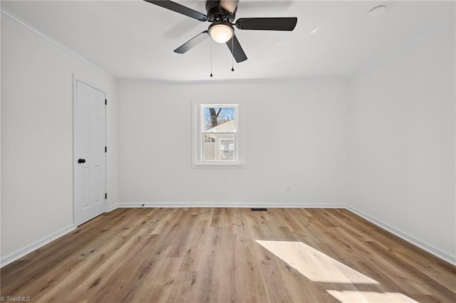 spare room featuring ceiling fan, crown molding, baseboards, and wood finished floors