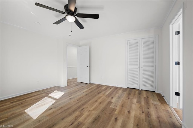 unfurnished bedroom featuring crown molding, ceiling fan, baseboards, wood finished floors, and a closet