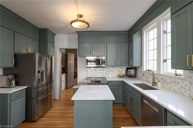 kitchen featuring a kitchen island, a sink, decorative backsplash, light countertops, and stainless steel appliances