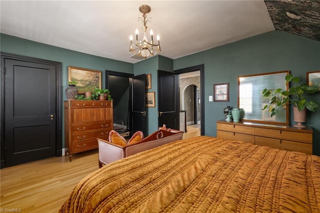 bedroom with arched walkways, a notable chandelier, light wood finished floors, and lofted ceiling