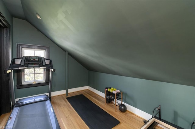 workout room with vaulted ceiling, baseboards, and wood finished floors