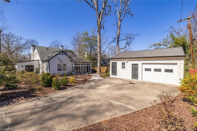 view of side of home with an outdoor structure, a detached garage, and driveway