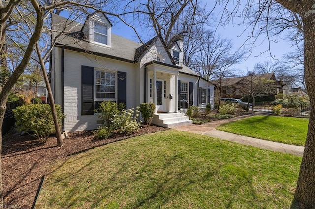 cape cod-style house with brick siding and a front lawn