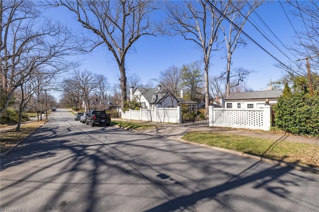 view of street featuring sidewalks, curbs, and a gate