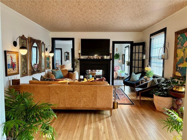 living area with a multi sided fireplace, a textured ceiling, crown molding, and light wood-style floors