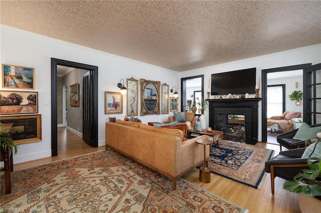 living room featuring hardwood / wood-style floors, crown molding, a multi sided fireplace, and a textured ceiling