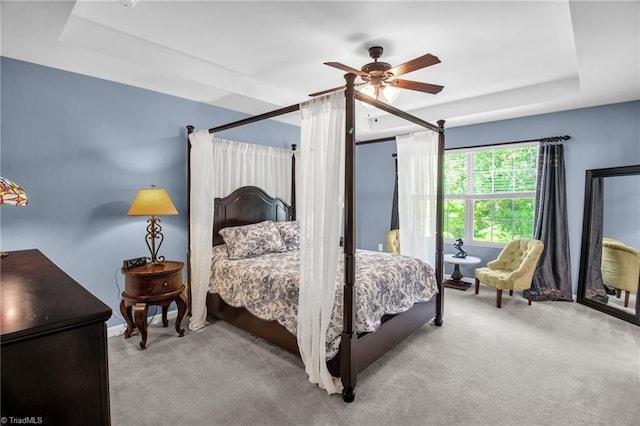 carpeted bedroom with a ceiling fan and a tray ceiling