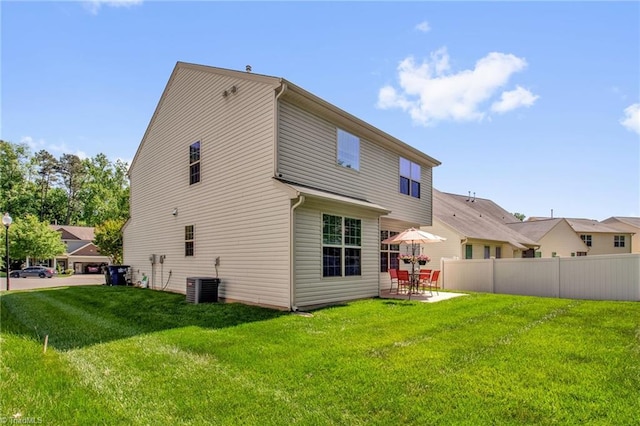 rear view of house featuring a yard, a patio, central AC, and fence