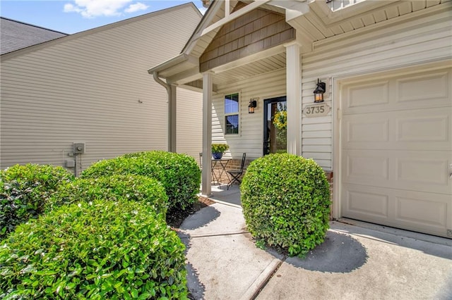 doorway to property featuring a porch, driveway, and a garage