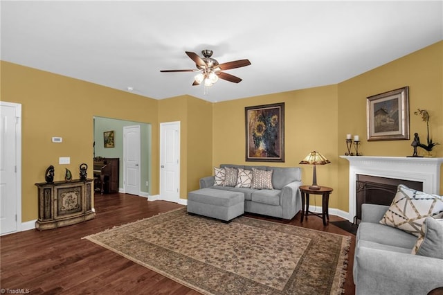 living room with dark wood-type flooring, baseboards, and ceiling fan