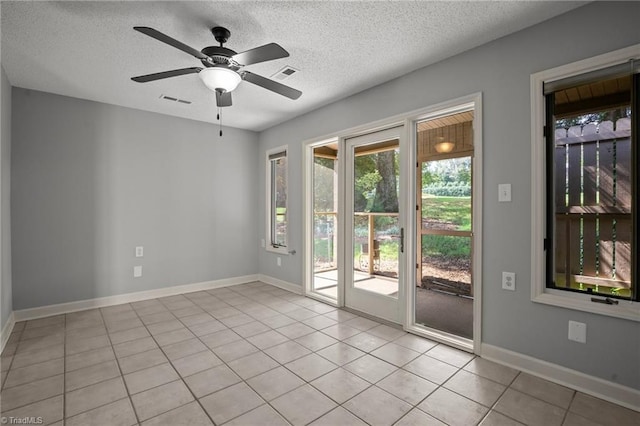 spare room featuring ceiling fan, light tile patterned floors, and a textured ceiling