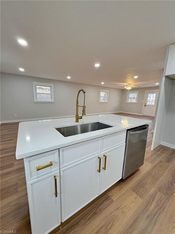 kitchen with wood finished floors, a sink, white cabinetry, open floor plan, and dishwasher