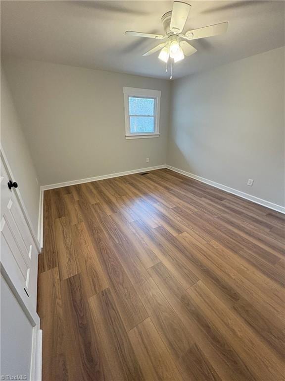 unfurnished room with dark wood-type flooring, visible vents, ceiling fan, and baseboards