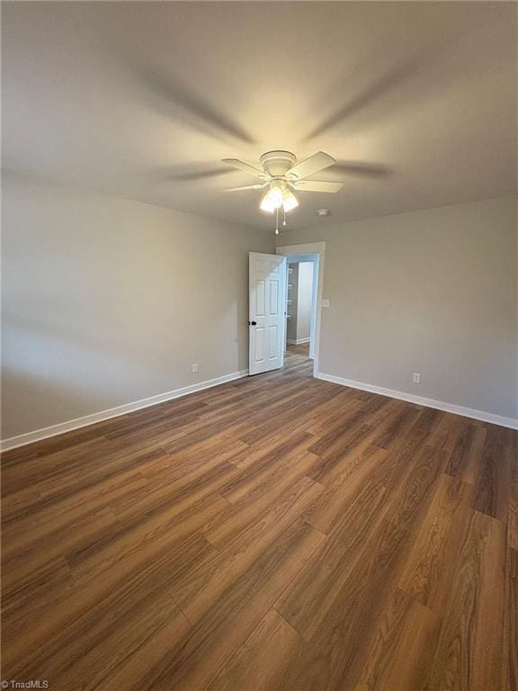 unfurnished room with baseboards, dark wood finished floors, and a ceiling fan